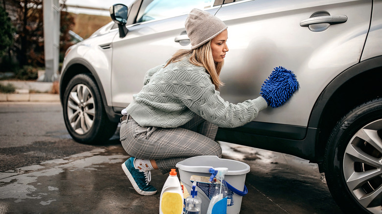 woman with cleaning products wiping white car