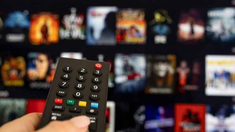 Person pointing remote at streaming service on TV