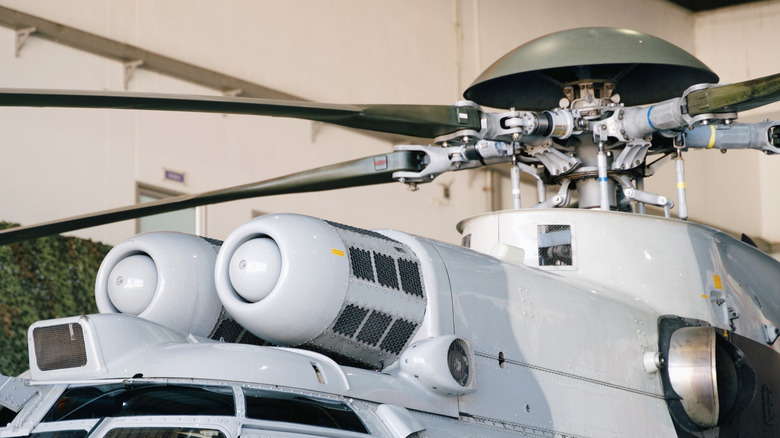 A close-up of a white helicopter's rotor blades and mast on a sunny day