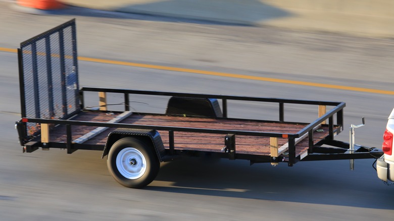 A car driving a tow trailer down a road.