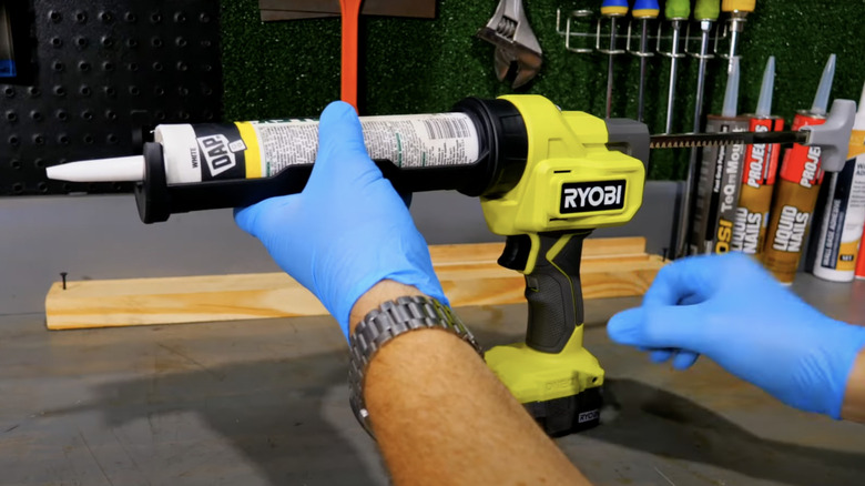 man holding Ryobi caulk gun with gloves