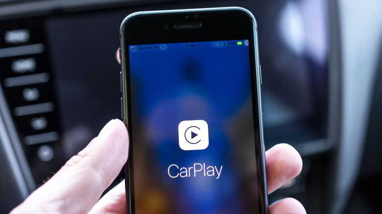 Person holding an iPhone 8 with Apple CarPlay icon on the screen