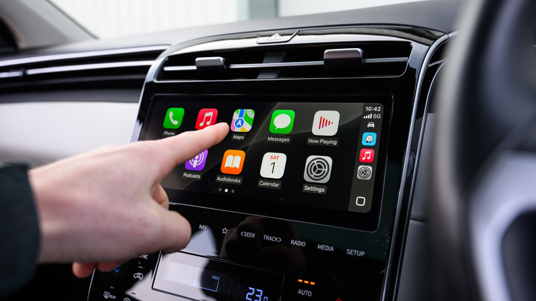 Person using an Apple CarPlay interface on a car's infotainment screen