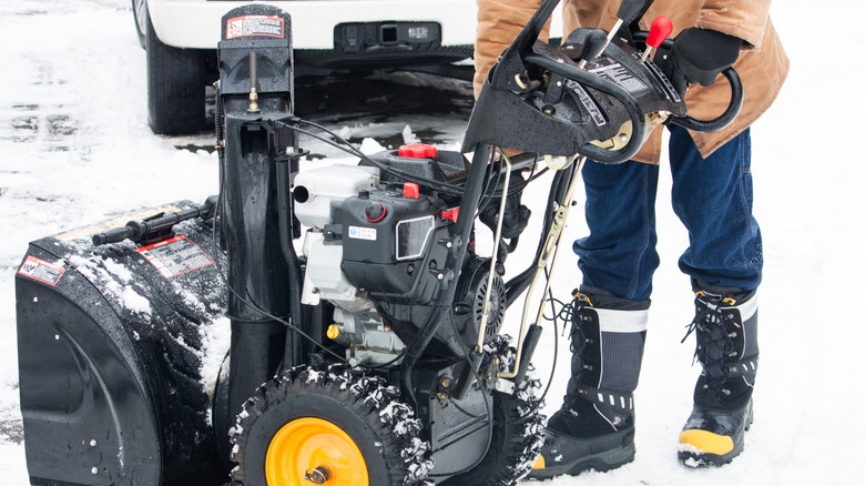 A person standing near a large snow blower