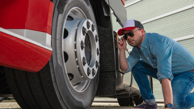 Trucker inspecting tires for problems.