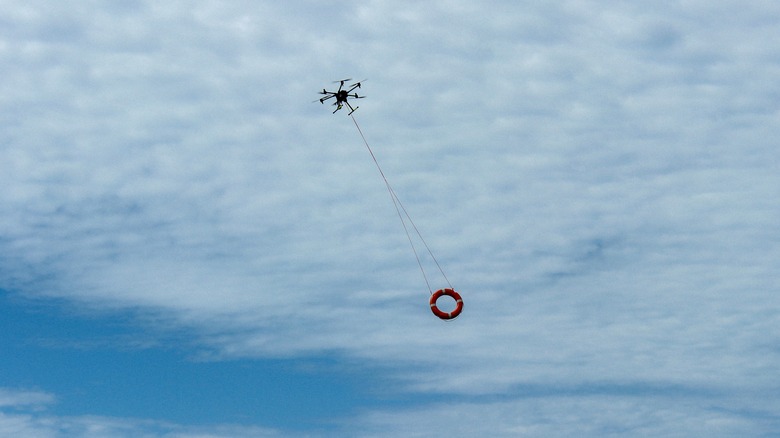 A drone flying in the air carrying a life buoy.