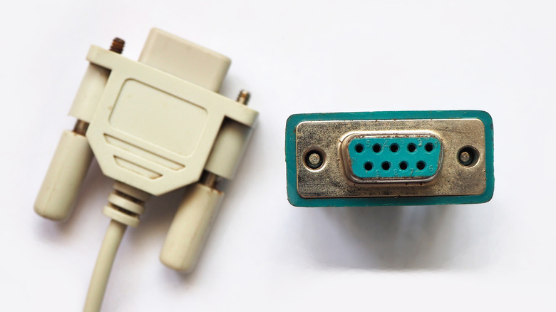 A serial port removed from its hardware on a white background next to a serial port cable.