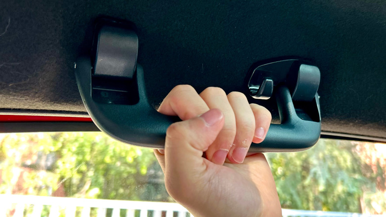 A person grabbing onto a car's grab handle.