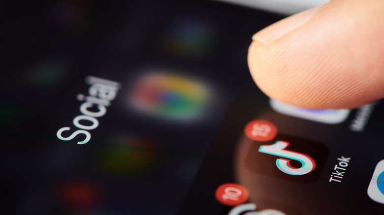 Close-up of a finger hovering over TikTok app icon