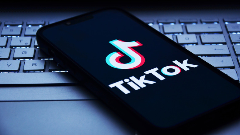 Smartphone showing TikTok logo on top of laptop keyboard