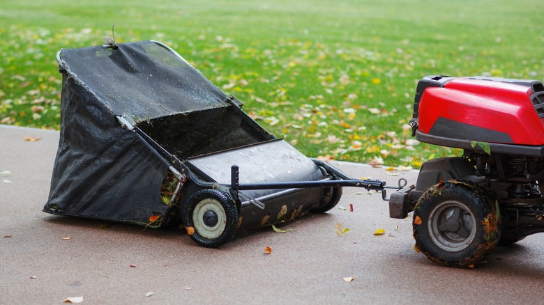 A lawn sweeper being pulled by a yard tractor