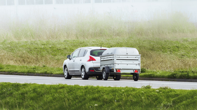 A car hauling a trailer on a foggy road
