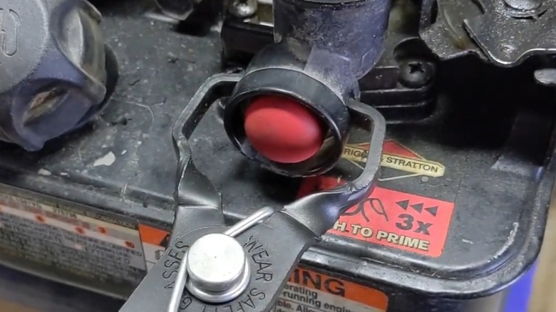 A person using a clamp to remove a primer bulb.