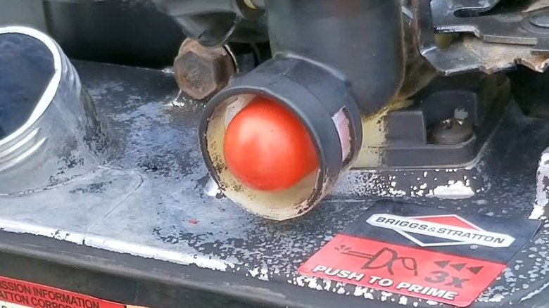 A red primer bulb on a lawn mower.