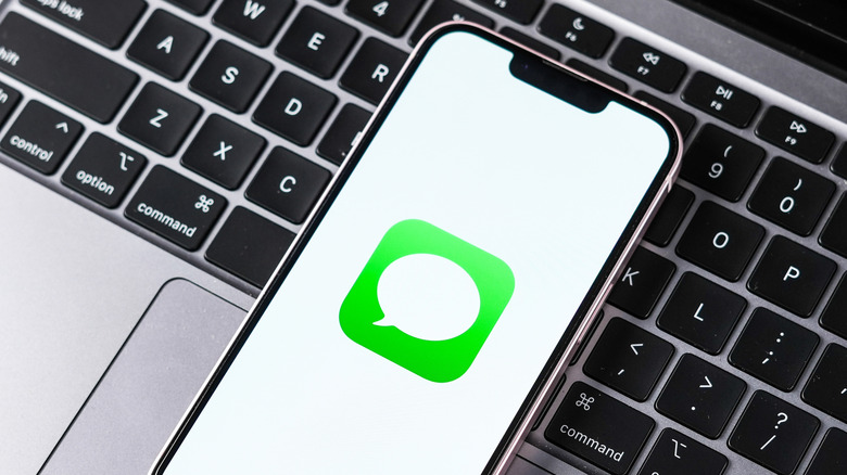 iPhone on a MacBook keyboard showing Messages app icon