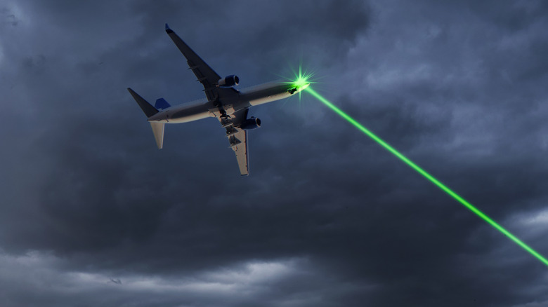 Graphic of a green laser beam striking the cockpit of an airplane.