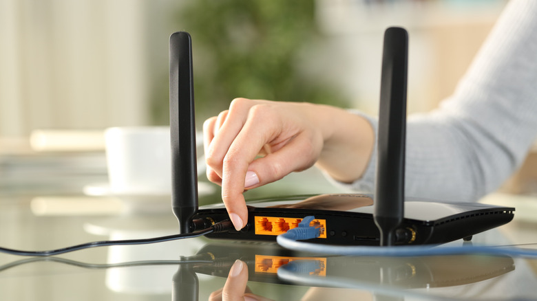 Person pressing the reset button on a router