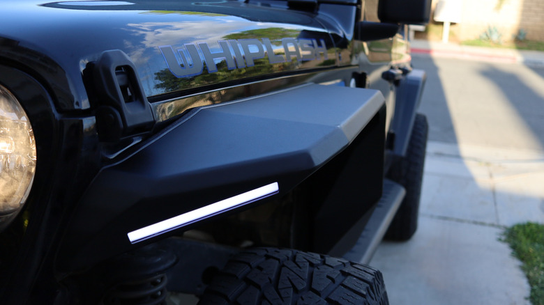 A black Jeep Wrangler with aftermarket fender flares, close-up of the fender flares themselves