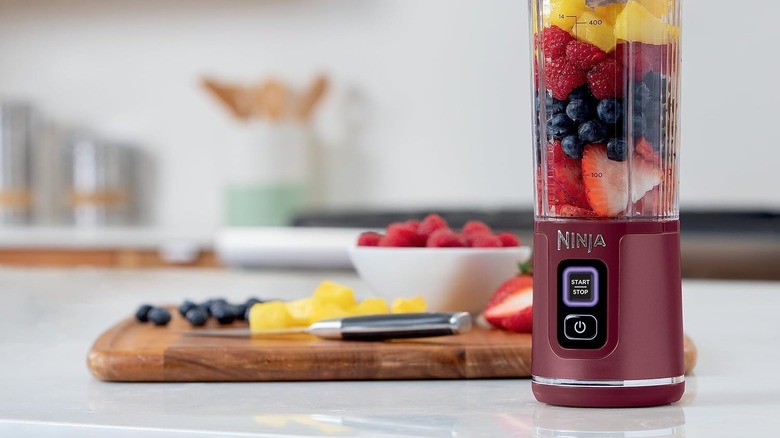 Ninja Blast Blender showing Start/Stop button LED blinking with sliced fruit in the background