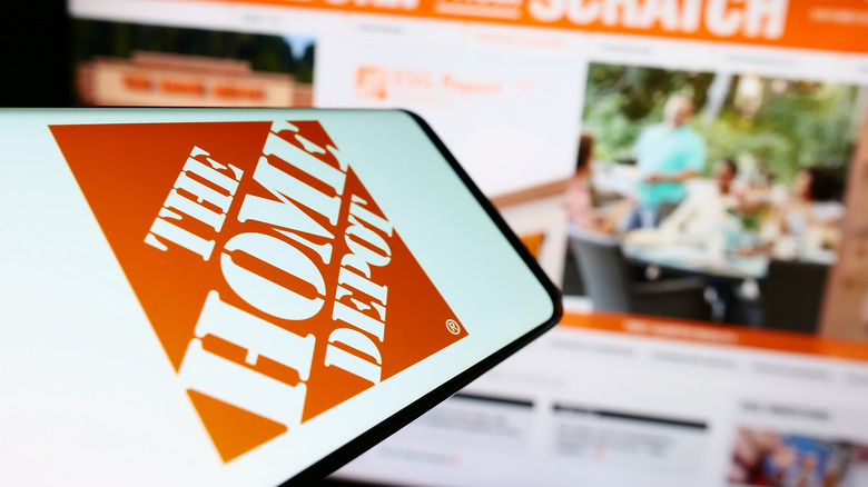 Home Depot logo on phone in front of website home page