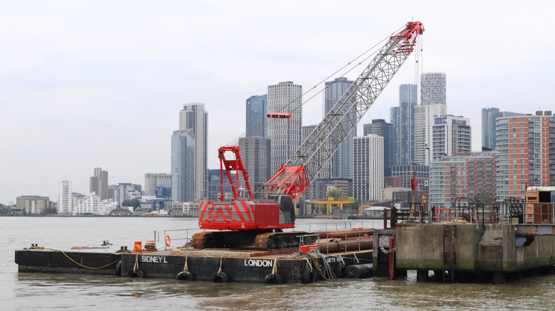 Red crane on barge named Syndey L lifting equipment from a pier