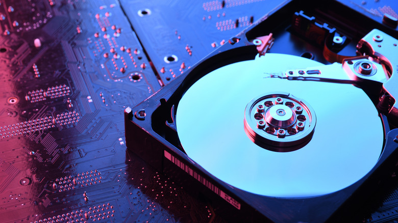 A hard drive (HDD) showing the disk on top of a red-blue motherboard.