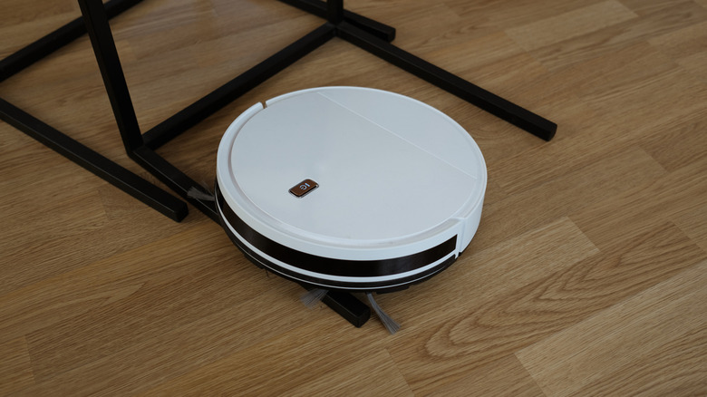 A robot vacuum that has beached itself on the leg of some furniture