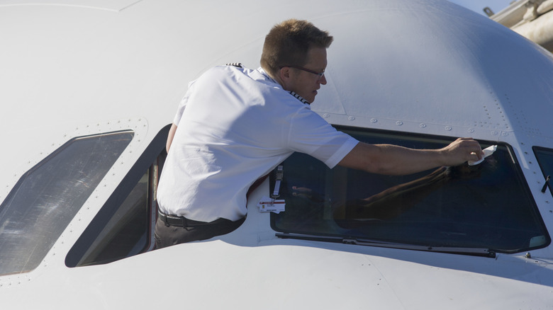 Pilot cleans an aircraft's windshield.