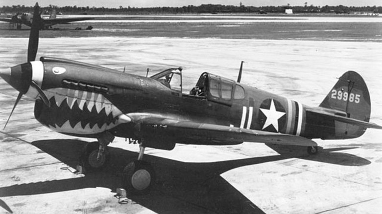 A black and white image of a P-40 combat plane on a turmac