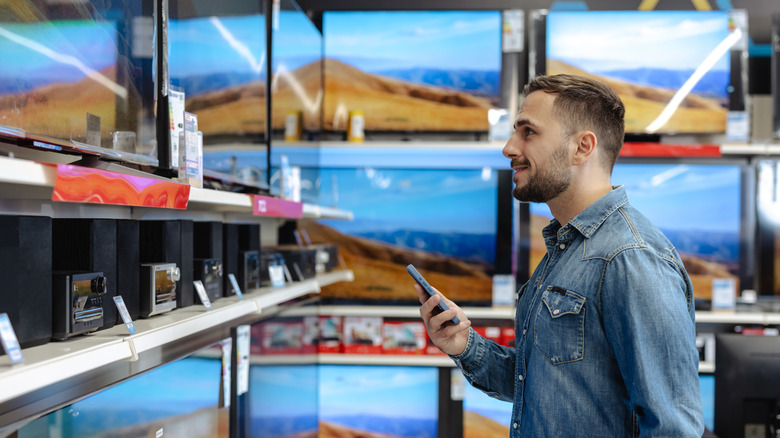 A man browsing TVs at an electronics store