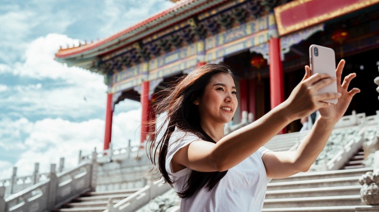 Woman taking picture of herself with phone while on vacation
