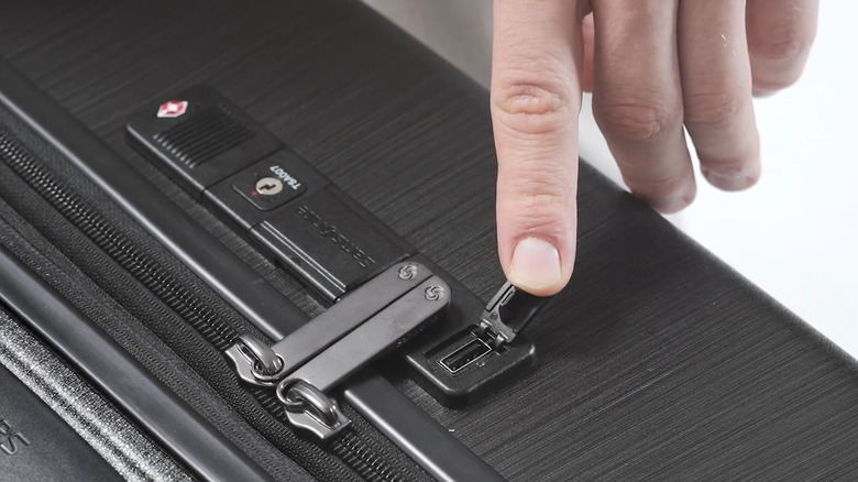 Hand pointing to USB port on a black suitcase
