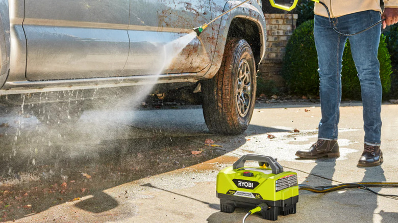 Person pressure washing car with Ryobi RY14AM12 pressure washer