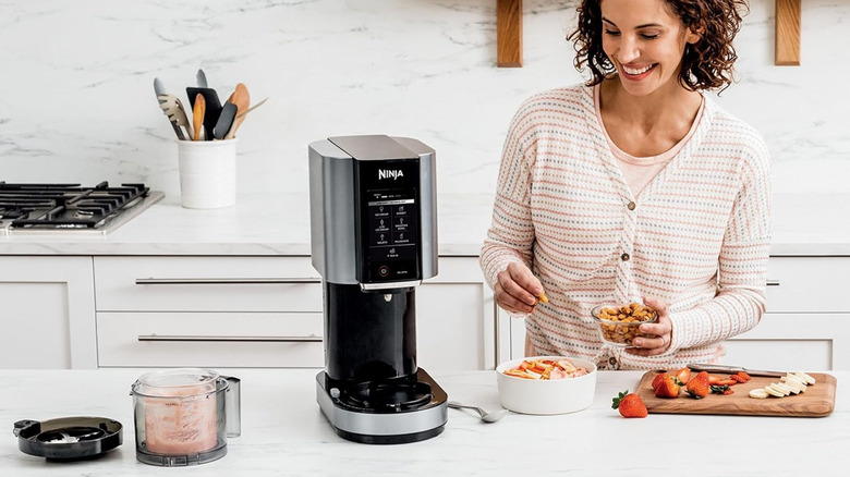 Woman using Ninja Creami to make smoothie bowl in the kitchen