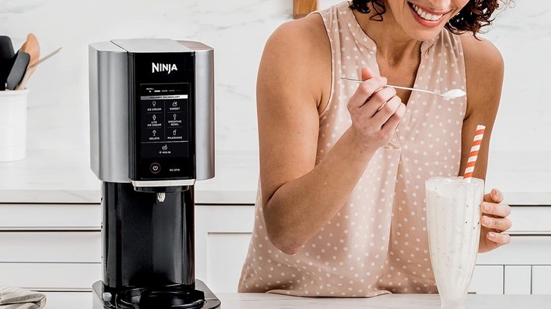 Woman scooping milkshake next to Ninja Creami