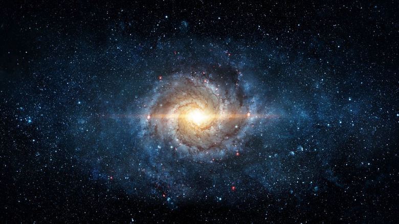 Space scene with stars in a swirling galaxy in the middle.