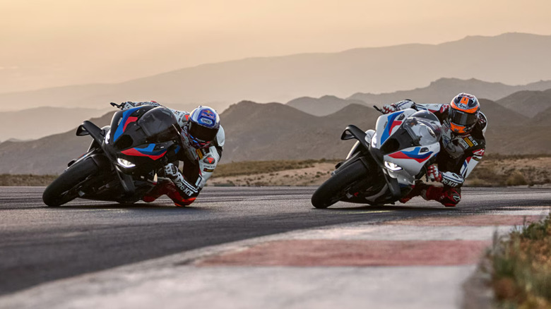 Two racers riding M1000RRs in Light White and Blackstorm Mettalic lean into a bend