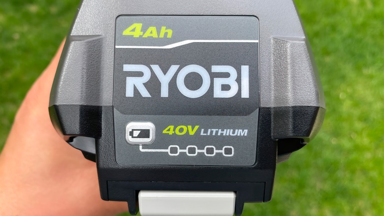 A person holding a 40V Ryobi battery outside.
