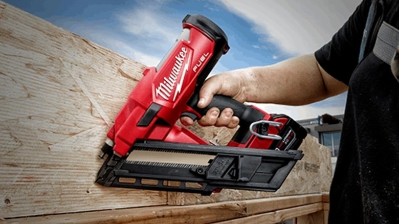 A person using a Milwaukee framing nailer