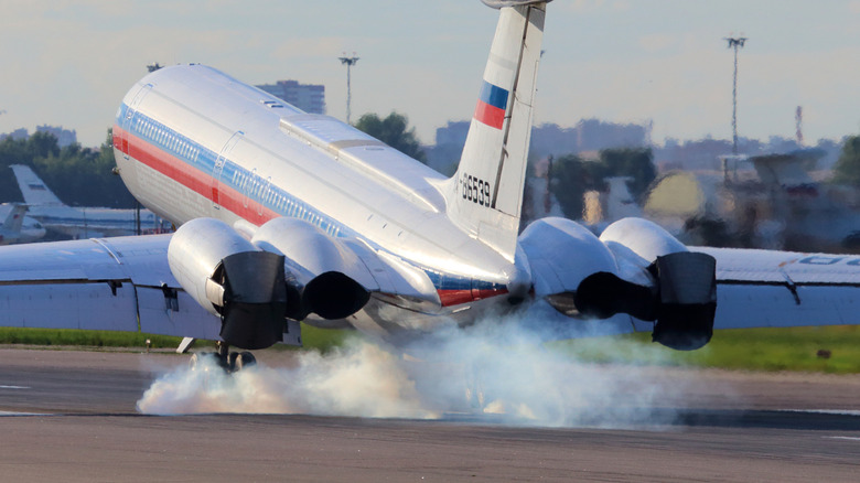 Smoke billowing from the rear of a landing jet plane