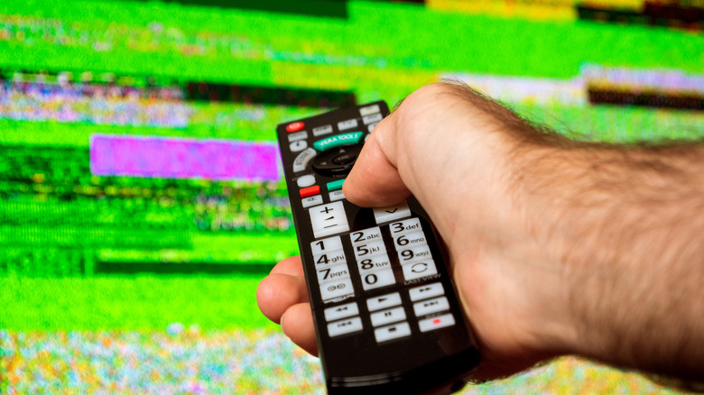 Hand pointing a remote at a malfunctioning display