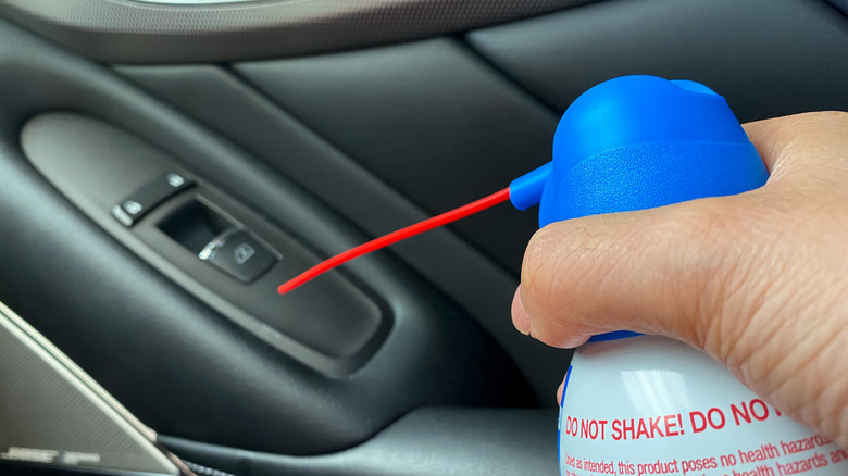 Person using a can of compressed air in a car