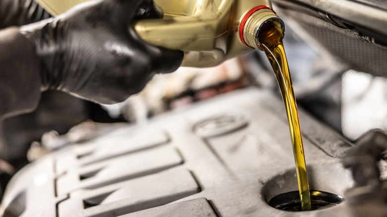 A mechanic topping un an engine with engine oil