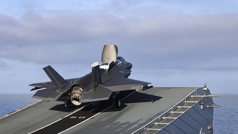 A F-35B launching from the HMS Queen Elizabeth with its vectored nozzle pointing down at the ski jump.