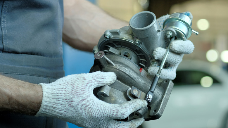 Mechanic with gloved hands holding a turbocharger