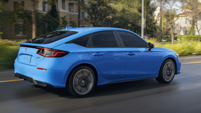 Blue 2025 Honda Civic hatchback driving in city.