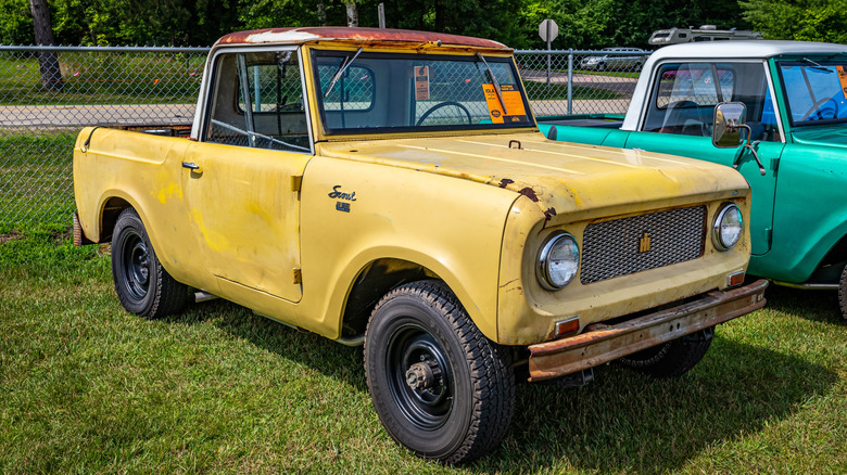 A rusty yellow 1961 International Scout parked at a car show