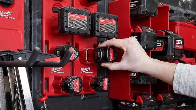 Hand touching gadget on Milwaukee battery rack