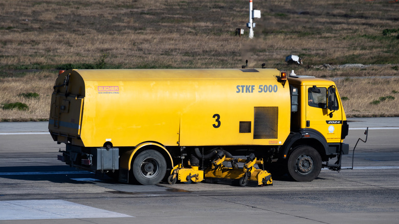 Airport maintenance vehicle cleaning rubber in landing zone of runway, right-side view