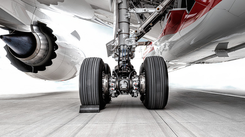 Left-side landing gear of passenger jet, rear view, parked with tire chock in-place